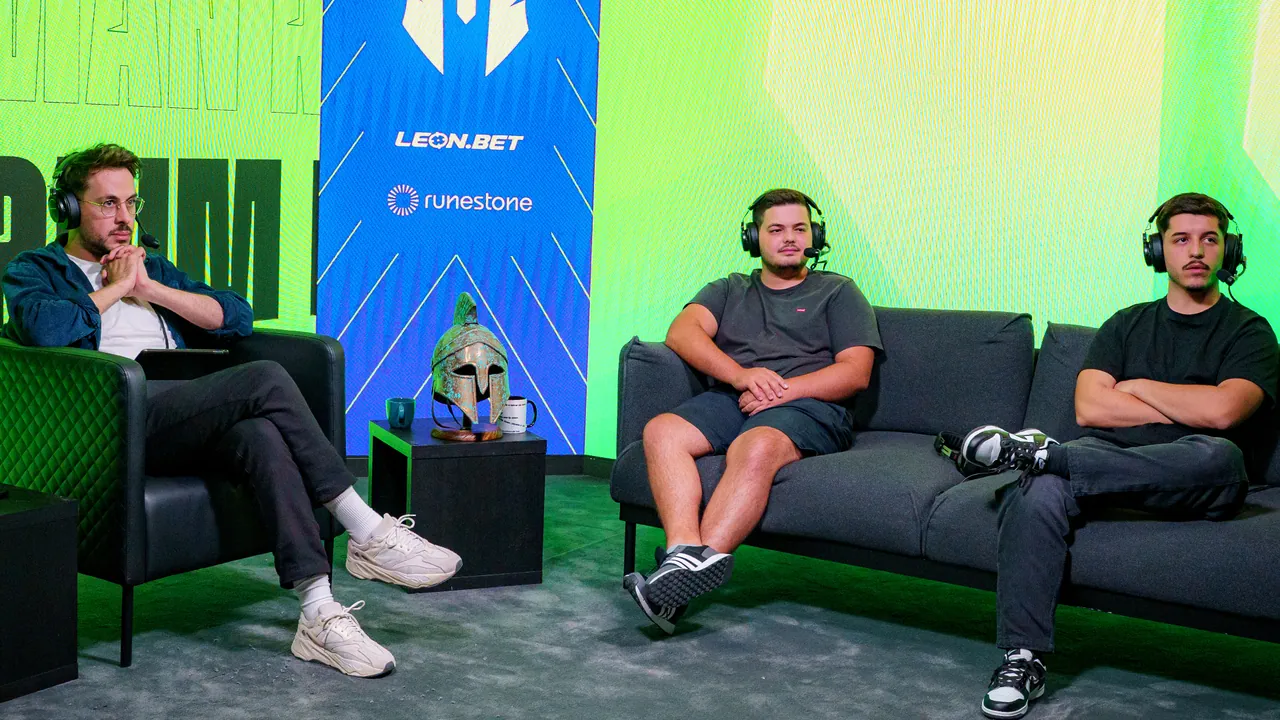 Três comentadores com auscultadores no estúdio do Roman Imperium Cup, diante do painel LED